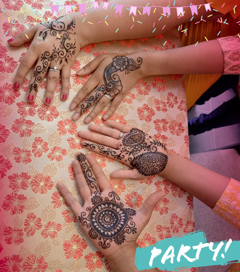 Decorated henna hands shown across a table
